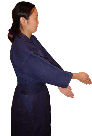 Woman in kendo uniform facing right, demonstrating arm position. Hands apart showing where to place on a shinai.